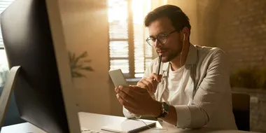 Hombre pensando mientras revisa su celular