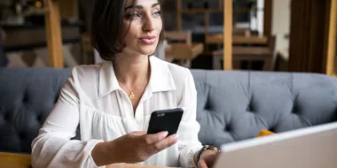 Mujer sonriendo mientras revisa su celular